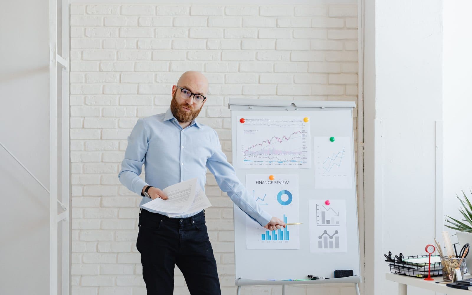 A man pointing to charts on a flip chart while presenting in a bright office